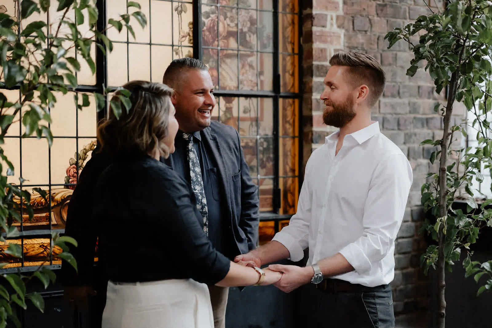 Josh Withers smiling as a couple hold hands during their Melbourne ceremony